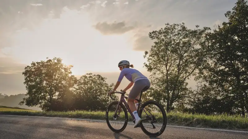 Rennradlerin fährt in den Sonnenuntergang Rennradlerin fährt in den Sonnenuntergang