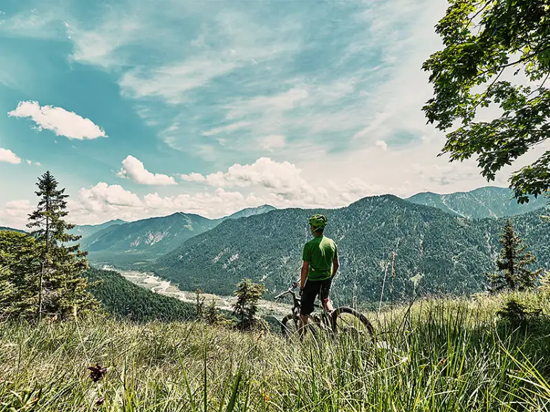 Mountainbiker auf Bergwiese mit Aussicht ins Tal Mountainbiker auf Bergwiese mit Aussicht ins Tal