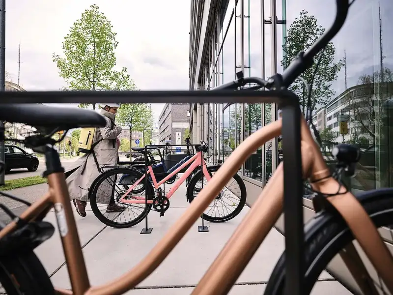 Eine Frau kommt mit ihrem Fahrrad am Büro an