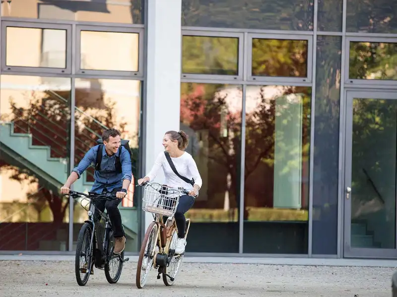 Zwei Radfahrer:innen fahren zufrieden in den Feierabend