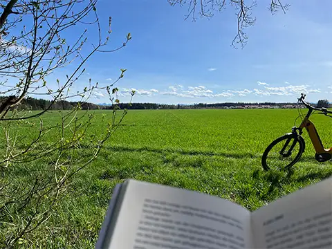 Mit dem JobRad und einem Buch bei einer Wiese im Sonnenschein Mit dem JobRad und einem Buch bei einer Wiese im Sonnenschein
