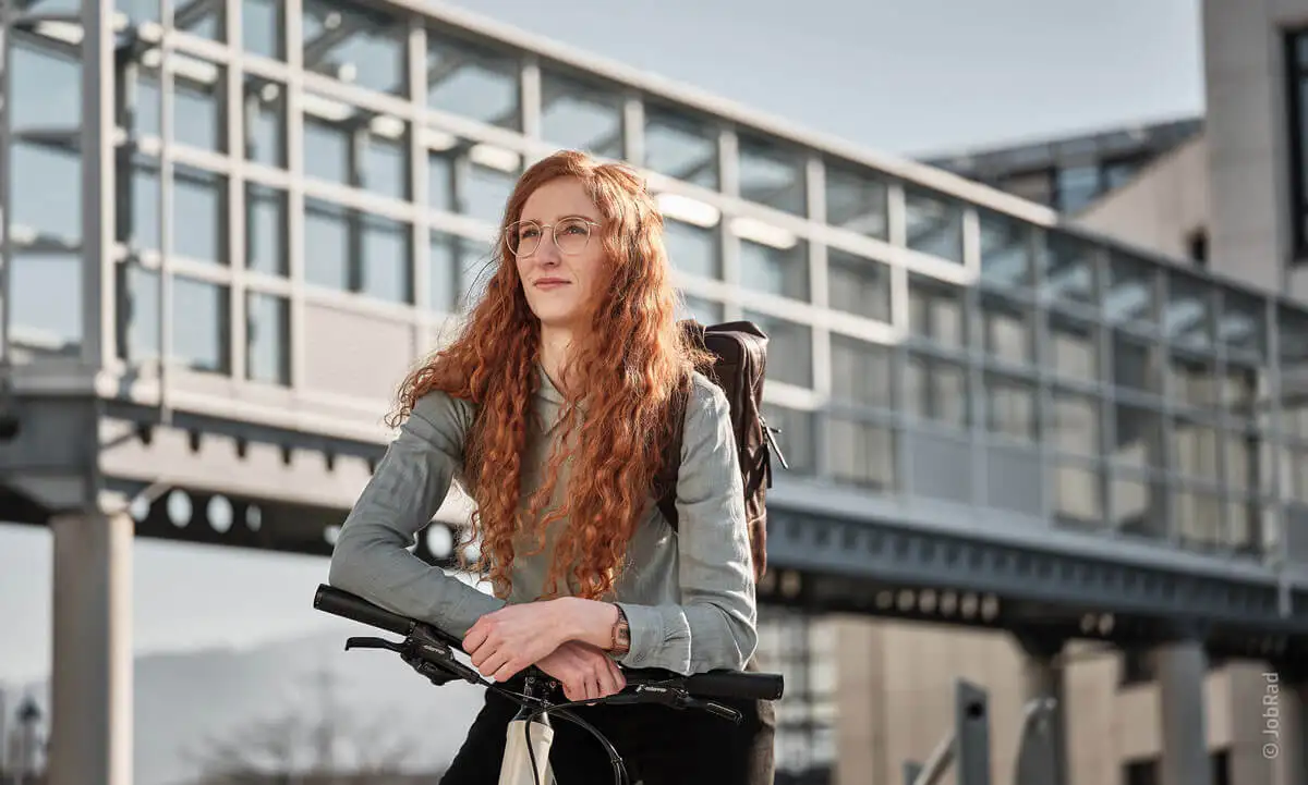 Eine nachdenkliche Frau mit roten Haaren auf ihrem Fahrrad