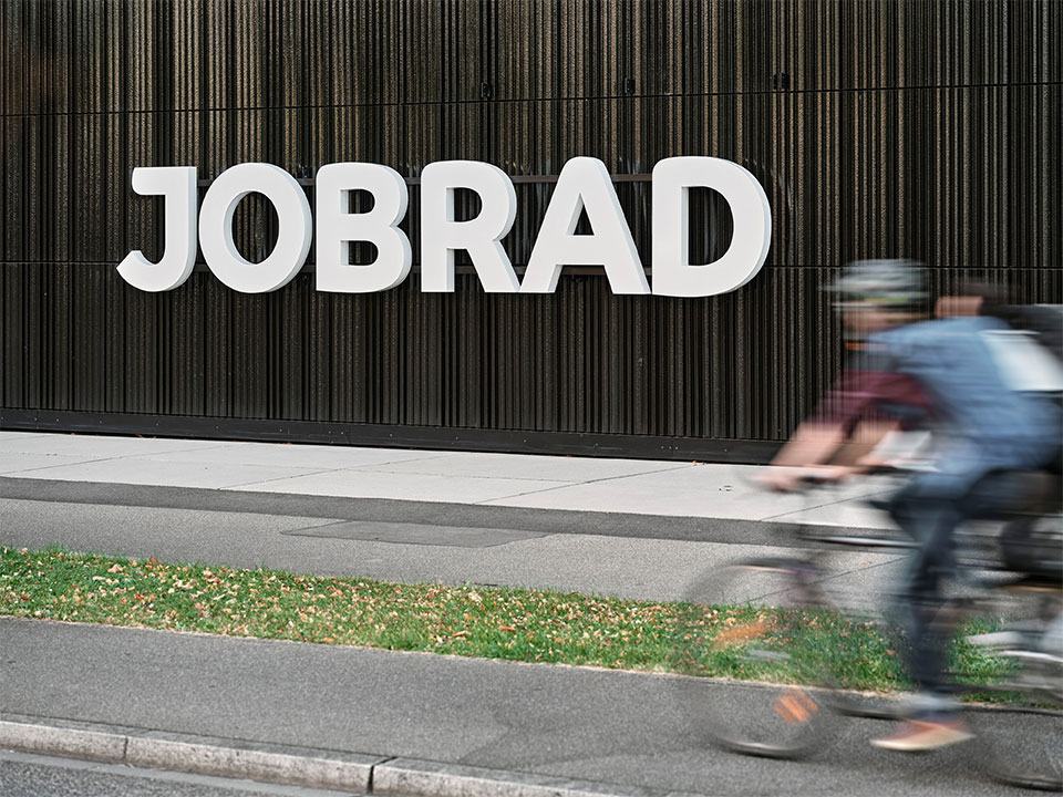 JobRad-Logo am Campus in Freiburg mit Bewegungsunschärfe von Radlern die vorbeidüsen